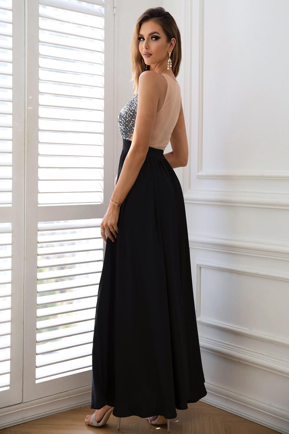  A stylish contrast sequin sleeveless maxi dress featuring a shimmering bodice with black and silver sequins flowing into a soft solid black skirt.