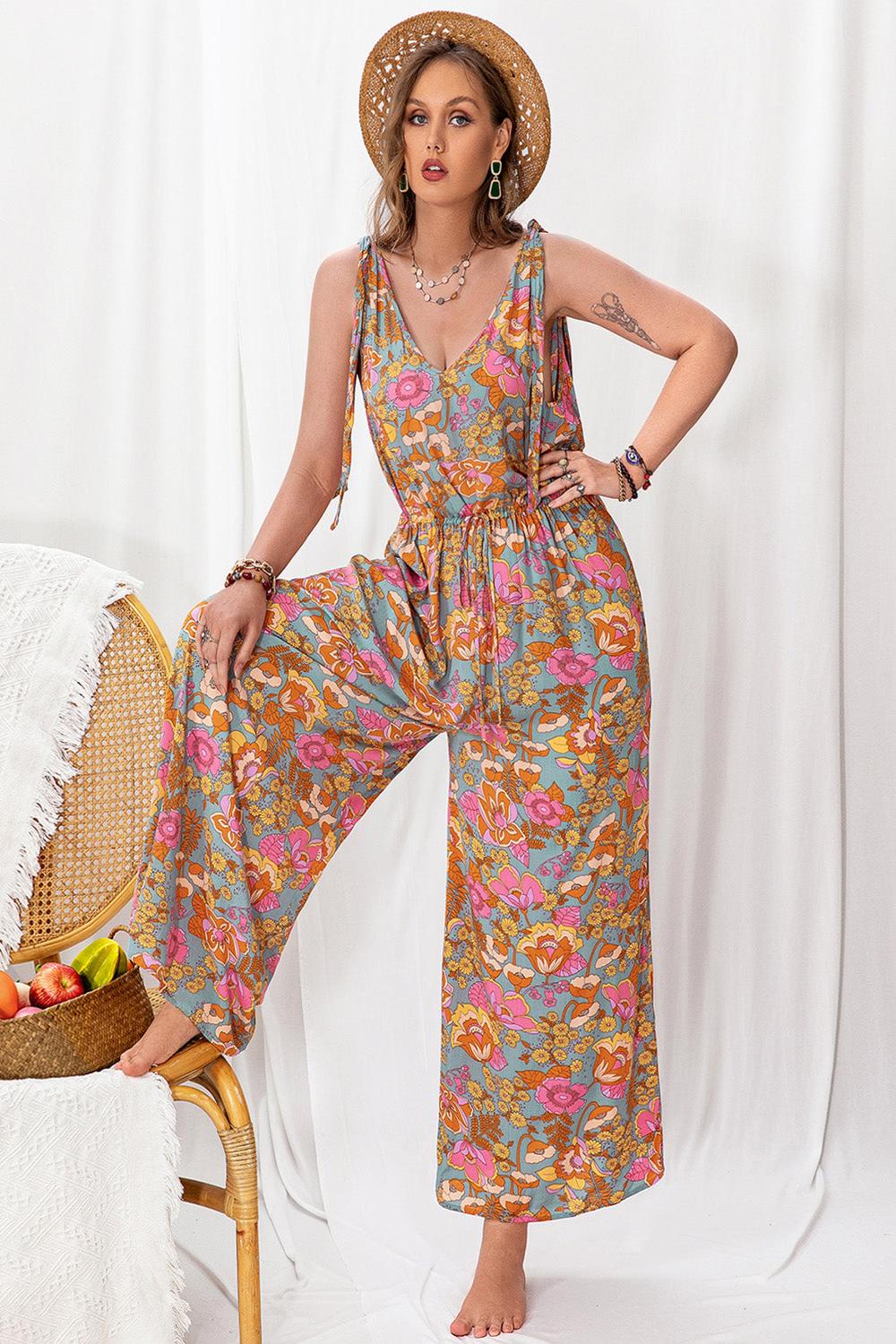 A stylish plussize woman wearing a colorful printed wideleg sleeveless jumpsuit featuring a flattering silhouette and a vibrant pattern standing against a neutral background.