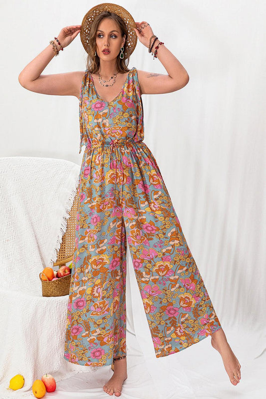 A stylish plussize woman wearing a colorful printed wideleg sleeveless jumpsuit featuring a flattering silhouette and a vibrant pattern standing against a neutral background.