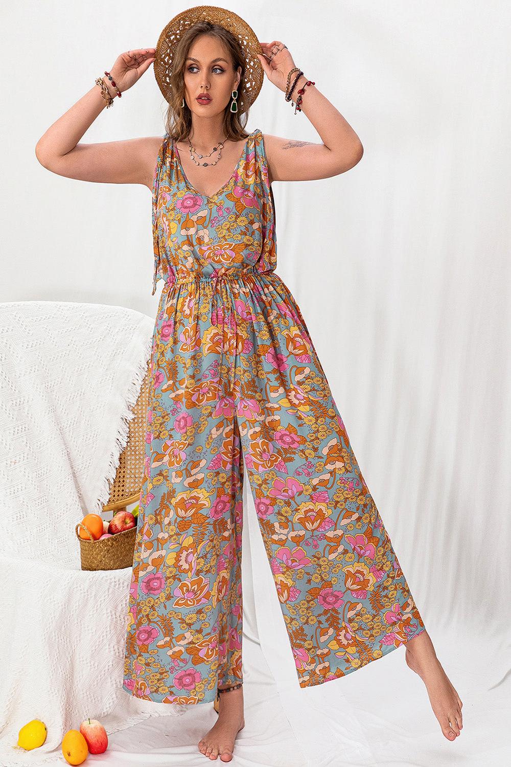 A stylish plussize woman wearing a colorful printed wideleg sleeveless jumpsuit featuring a flattering silhouette and a vibrant pattern standing against a neutral background.