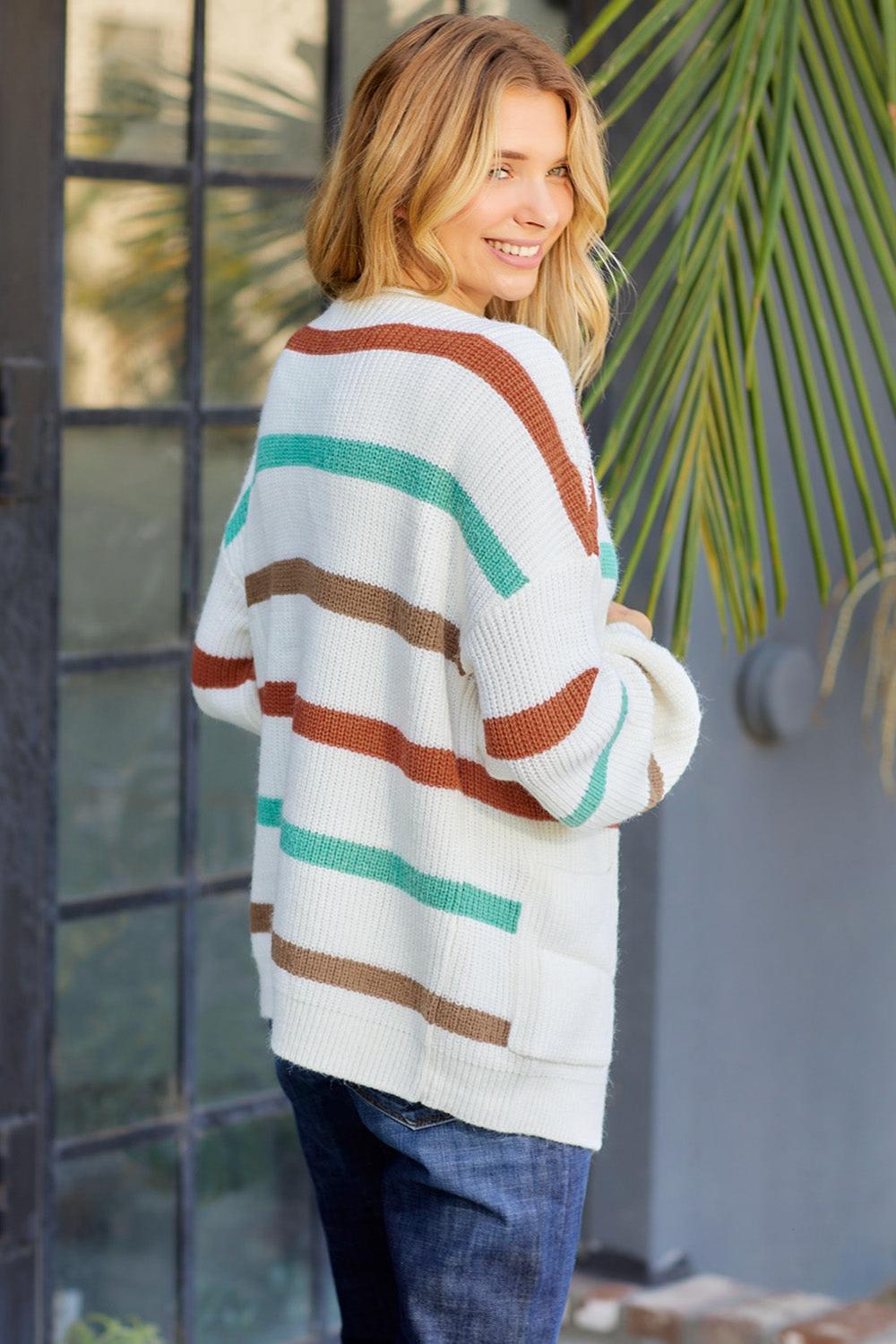  Striped open front cardigan with dropped shoulders featuring a blend of soft colors and a relaxed fit draped over a neutral background.